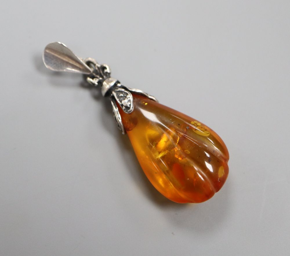 A silver and amber pendant with inclusions,